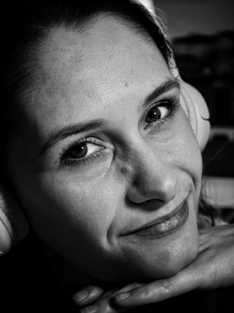 czarno biale zdjecie twarzy młodej dziewczyny lekko uśmiechnięteh w słuchawkach