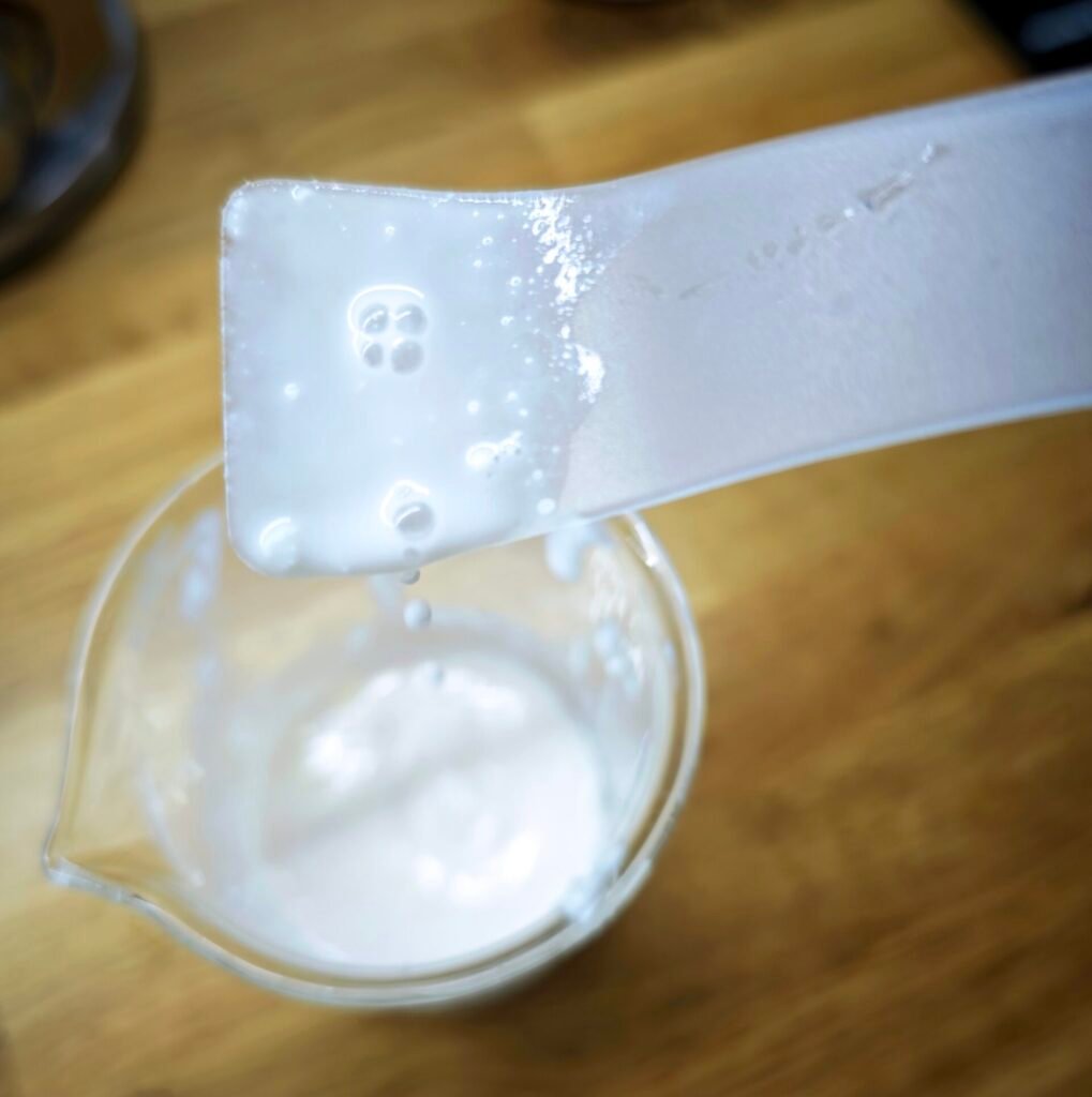 zdjęcie rozwarstionego kremu grudki pływające w zlewce